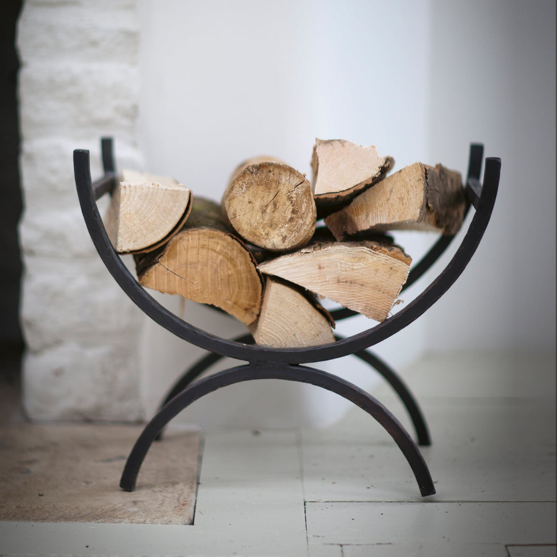 wrought iron log holder with feet and curved body